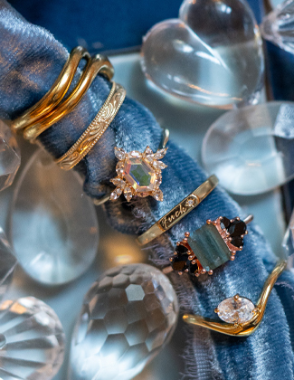 Assorted gold rings on rolled up light blue velvet fabric with a badge that reads 20% off