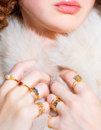 Close up of a woman wearing white fur with several gold rings on her hands with a badge that reads 20% off
