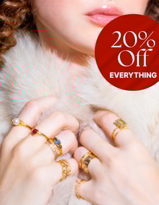 Close up of a woman wearing white fur with several gold rings on her hands with a badge that reads 20% off