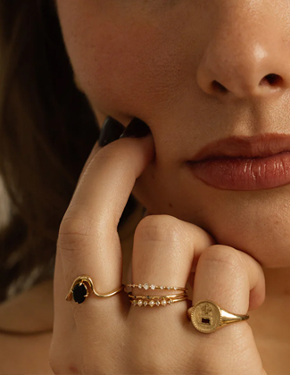 Close up of a woman's hand wearing a stack of solid gold rings