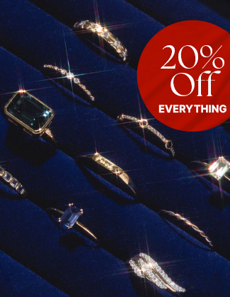 Assorted gold gemstone rings sitting in a dark blue velvet ring holder with a badge that reads 20% off