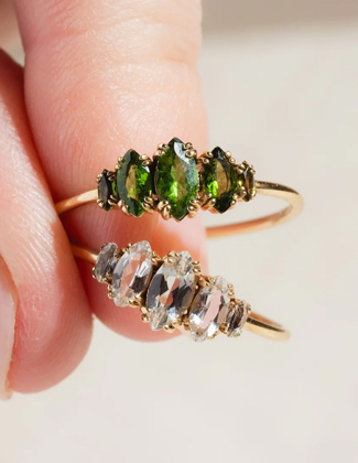 Two gold gemstone rings being pinched between fingers