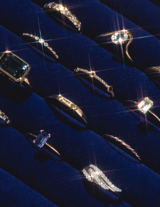 Assorted gold gemstone rings sitting in a dark blue velvet ring holder with a badge that reads 20% off