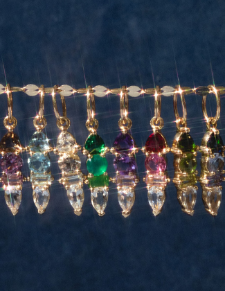 Assorted gold charms on a gold chain laying on light blue velvet fabric with a badge that reads 20% off