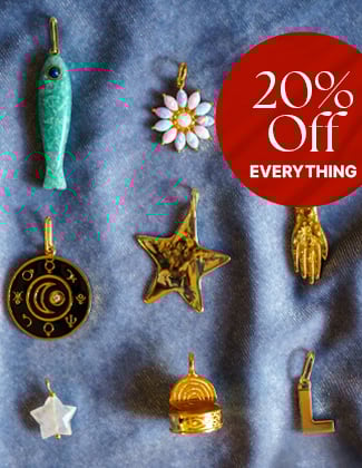 Assorted gold charms laying on light blue velvet fabric with a badge that reads 20% off