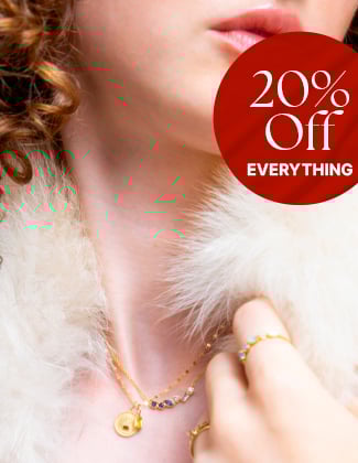 A close up of a woman wearing whote fur with three layered gold necklaces with a badge that reads 20% off
