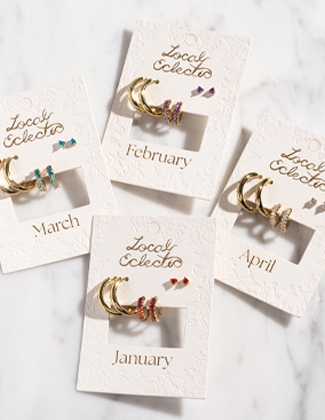 Four sets on birthstone earrings on carding laying on a marble backgorund