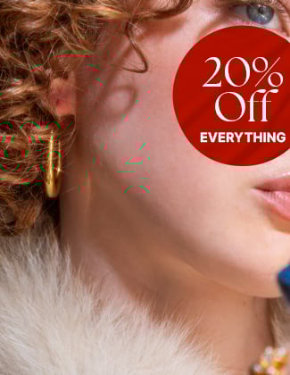 A close up of a woman wearing gold hoop earrings with a badge that reads 20% off