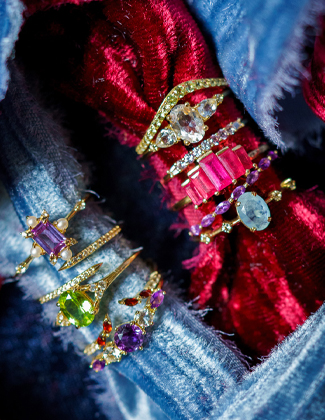 Gold gemstone rings laying on blue and red crished velvet fabric with a badge that reads 20% off