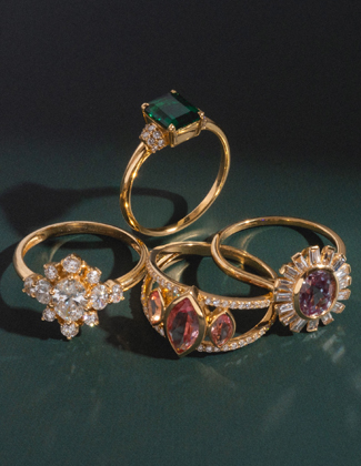 A close up of gold and gemstone rings on a dark green background