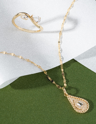 clear gemstone and gold jewelry on a white and green background