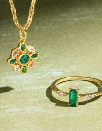 Close up of gold and green gemstone necklace on a light green background