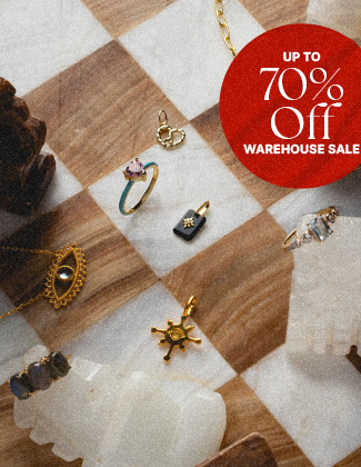 Gold gemstone jewelry laying on a woodgrain and white chess board