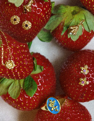Gold gemstone jewelry sitting on strawberries