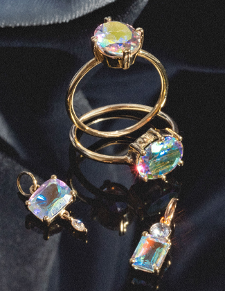 Gold jewelry with angel aura quartz stones sitting on a dark surface