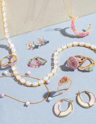 A selection of gold and opal jewelry laying on a light blue surface
