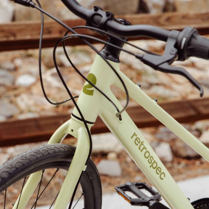 Close-up of a pastel green retro bicycle frame featuring "retrospec" branding with handlebars and cable lines visible.