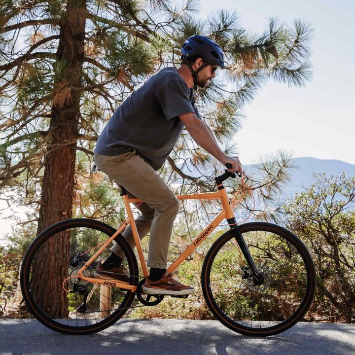 Person cycling on an bright yellow bike with trees and mountains in the background.