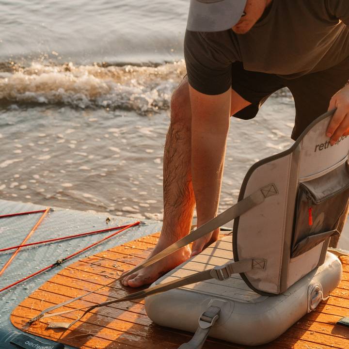 A man prepares an inflatable kayak seat on the Weekender Crew Inflatable Paddle Board.