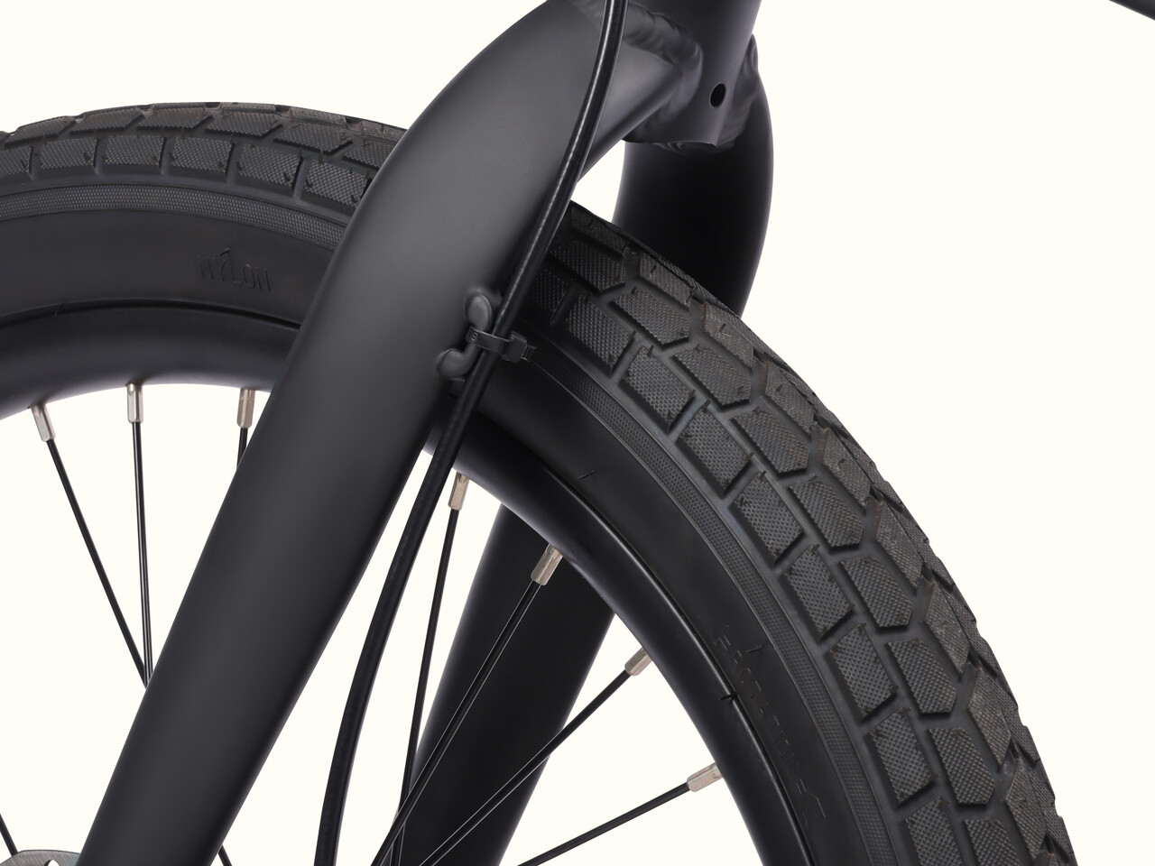 Close-up of a the Judd Rev 2 Folding Electric Bike's fork and tire, showcasing detailed tread patterns and metallic spokes against a neutral background.