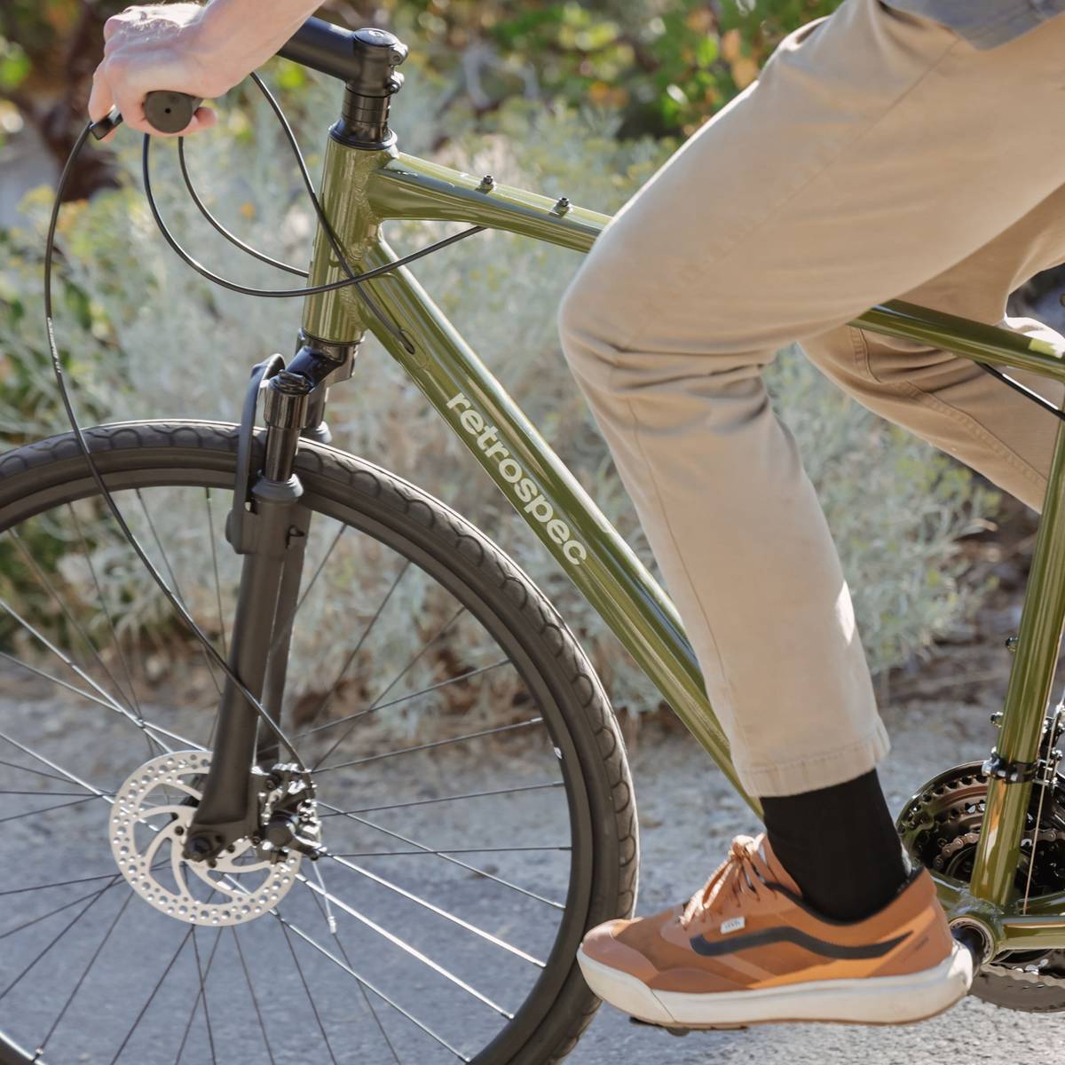 Close-up of a person riding an olive green Barron Plus Comfort Hybrid Bike - 21 Speed.