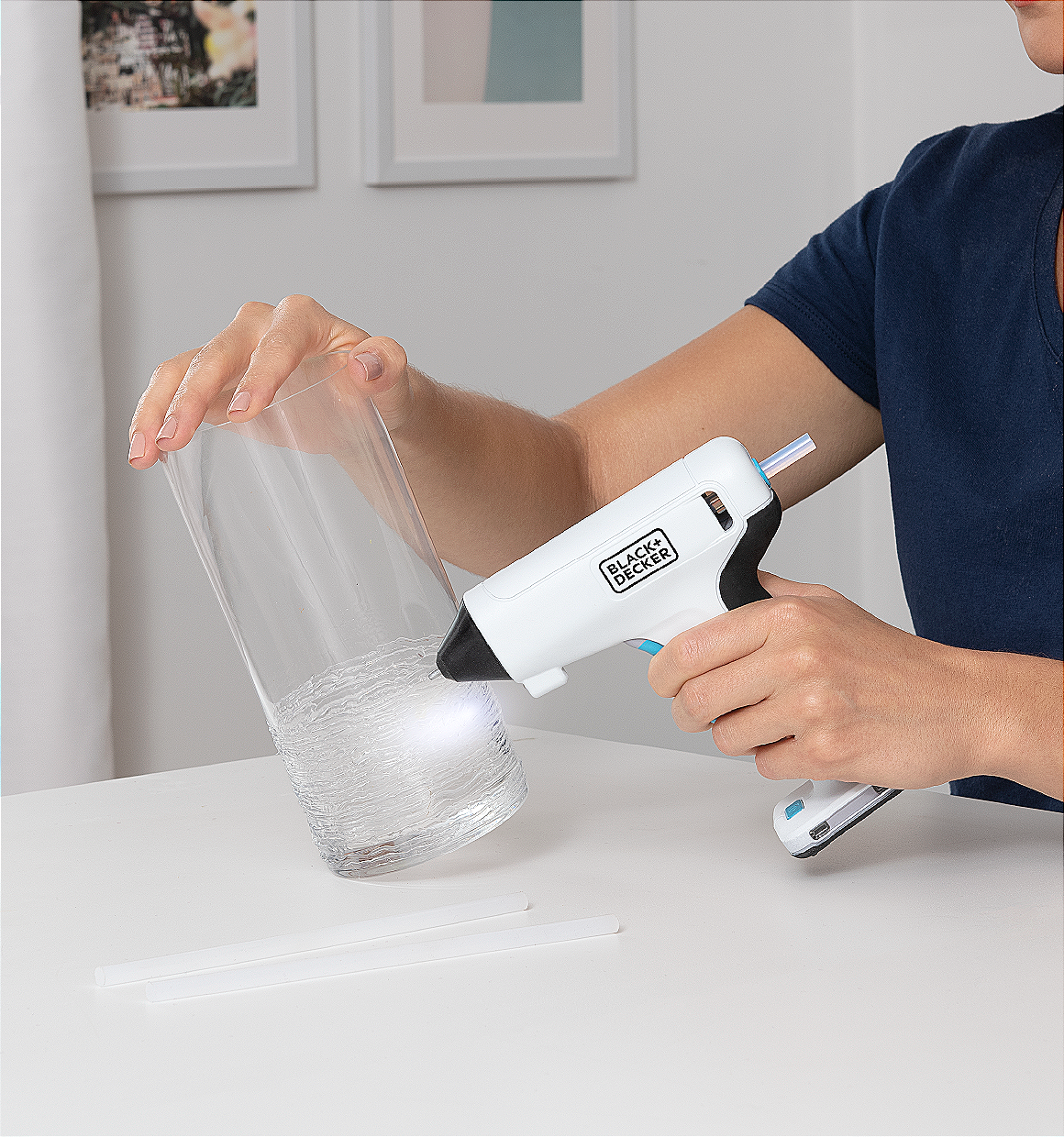 woman using a BLACK+DECKER cordless glue gun to decorate a vase.