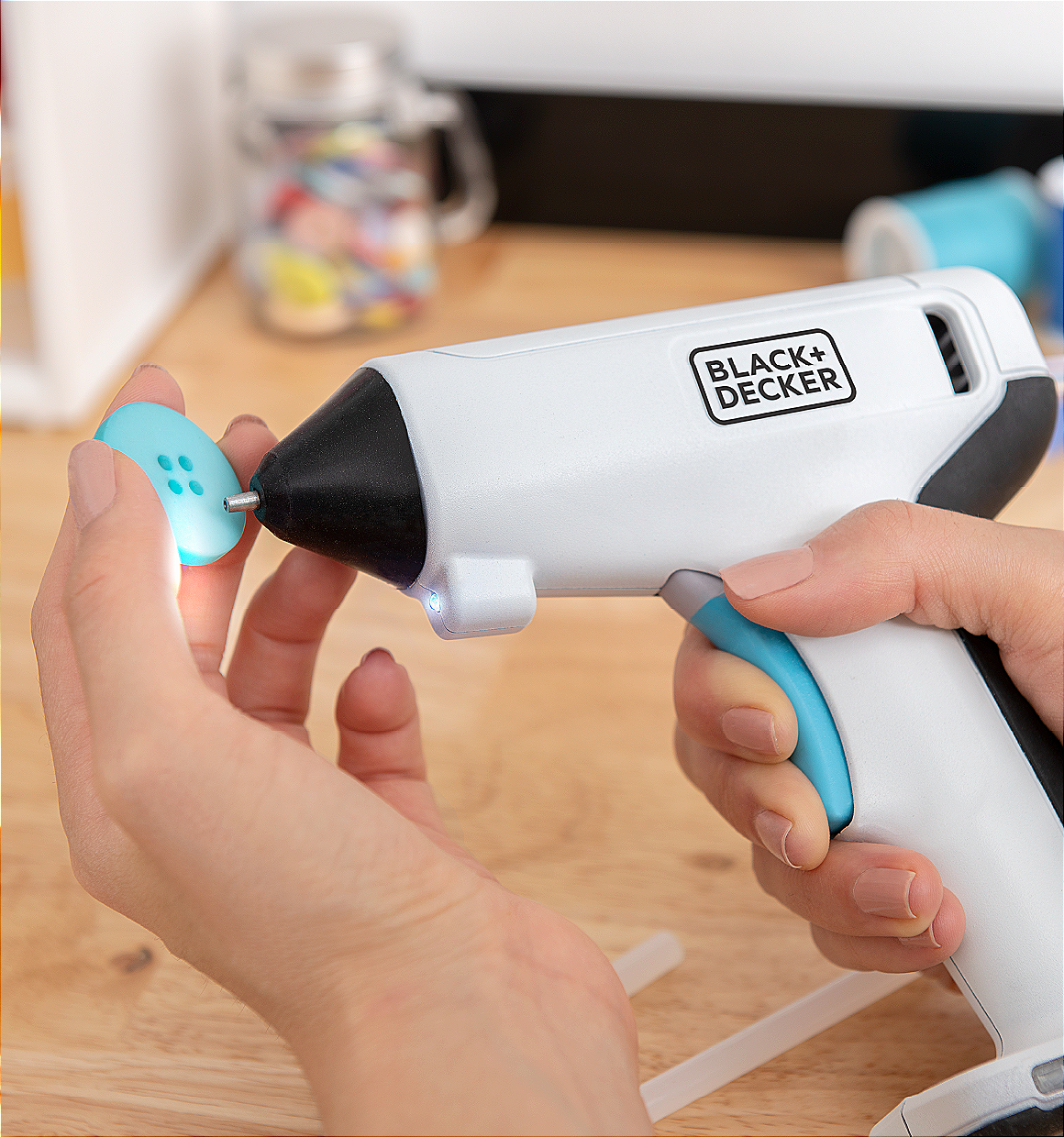 close-up of a BLACK+DECKER cordless glue gun being used to add glue to a decorative button