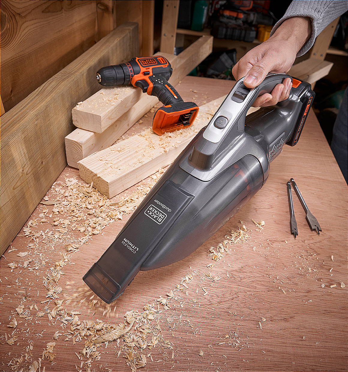 20V powerconnect hand vacuum being used to clean up sawdust from workshop table next to a drill driver.