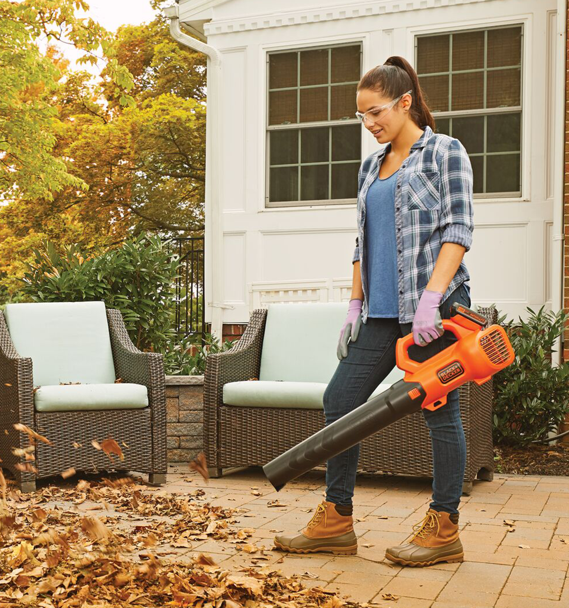 Person using Black and decker 20V Max* Leaf Blower to clean leaves off of a patio.