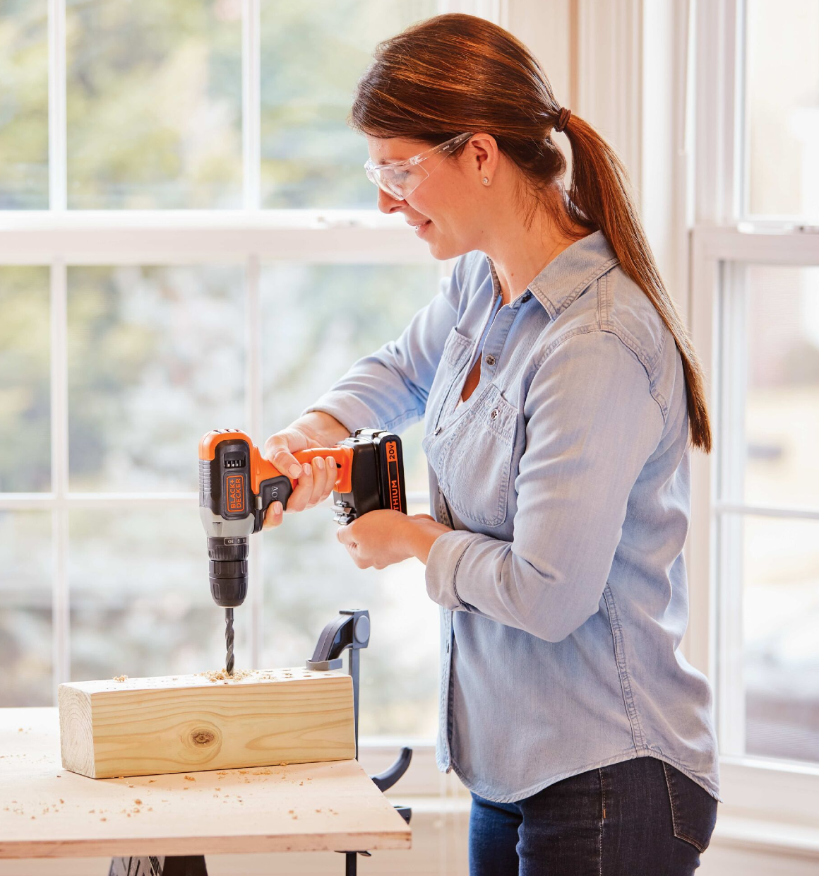 Woman using 20V Max Cordless Drill  to drill holes in a wooden block.