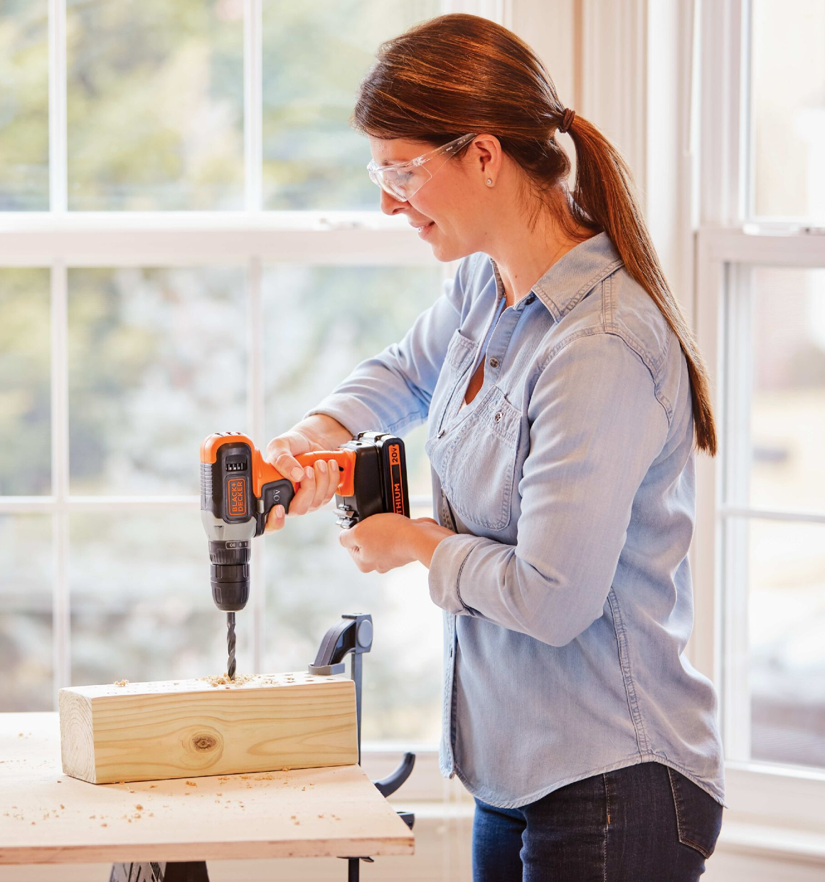 Woman using 20V Max Cordless Drill to drill holes in a wooden block.