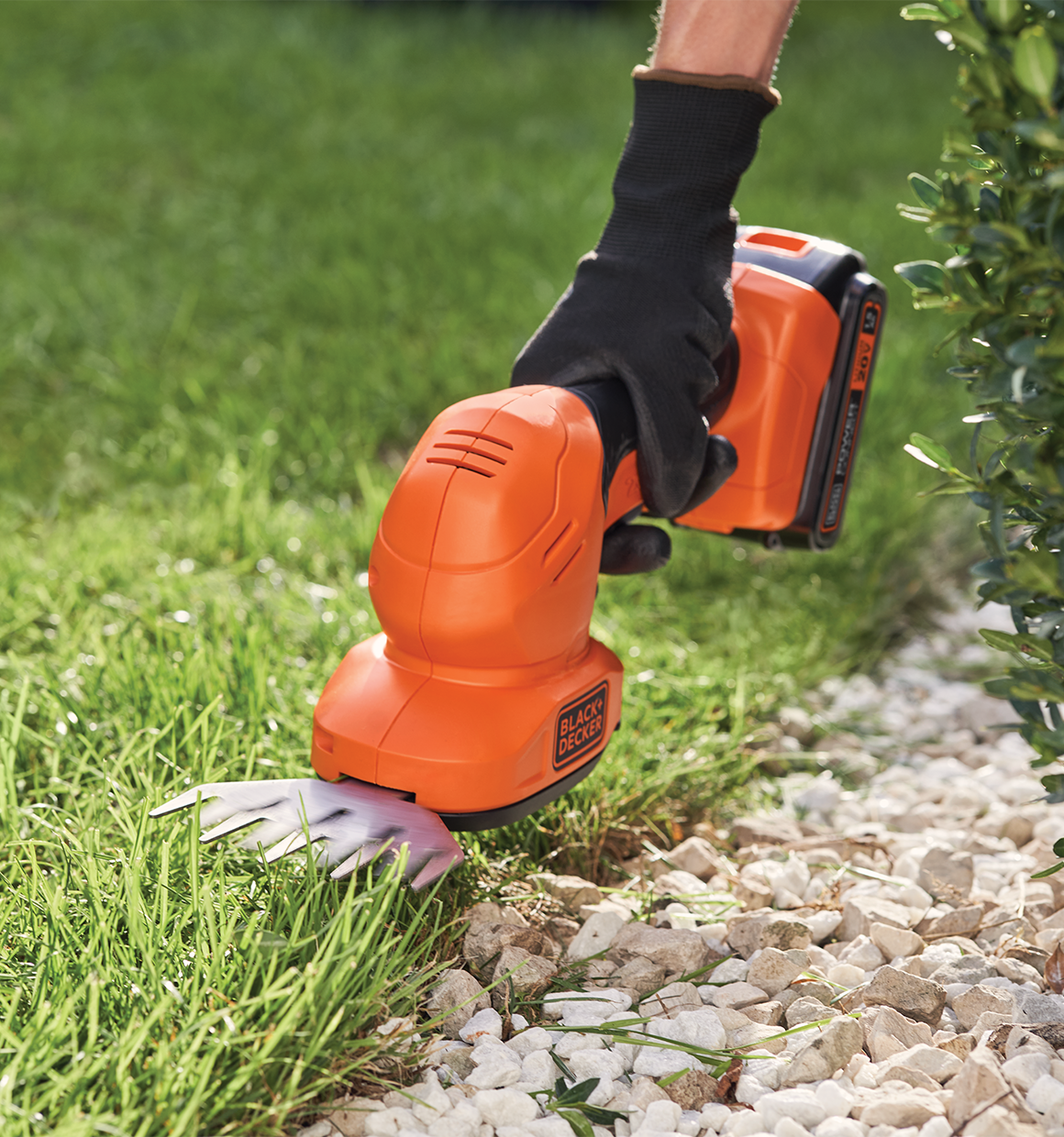 20 volt MAX shear shrubber being used by a person to trim grass.