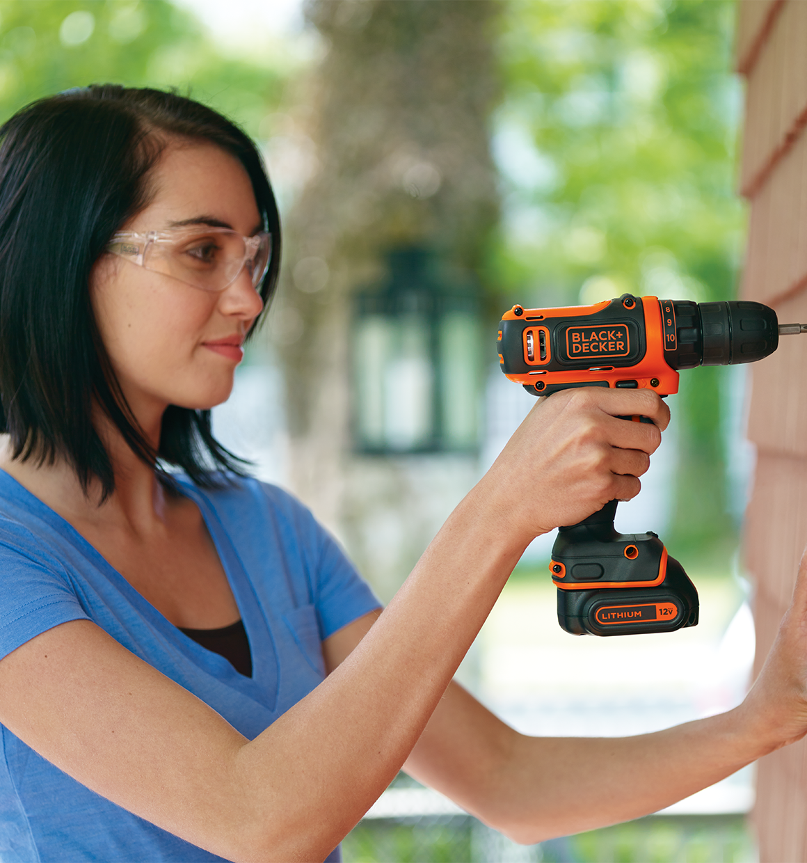 Woman using a 12V Max Drill/Driver to make a repair on the outside of a house.