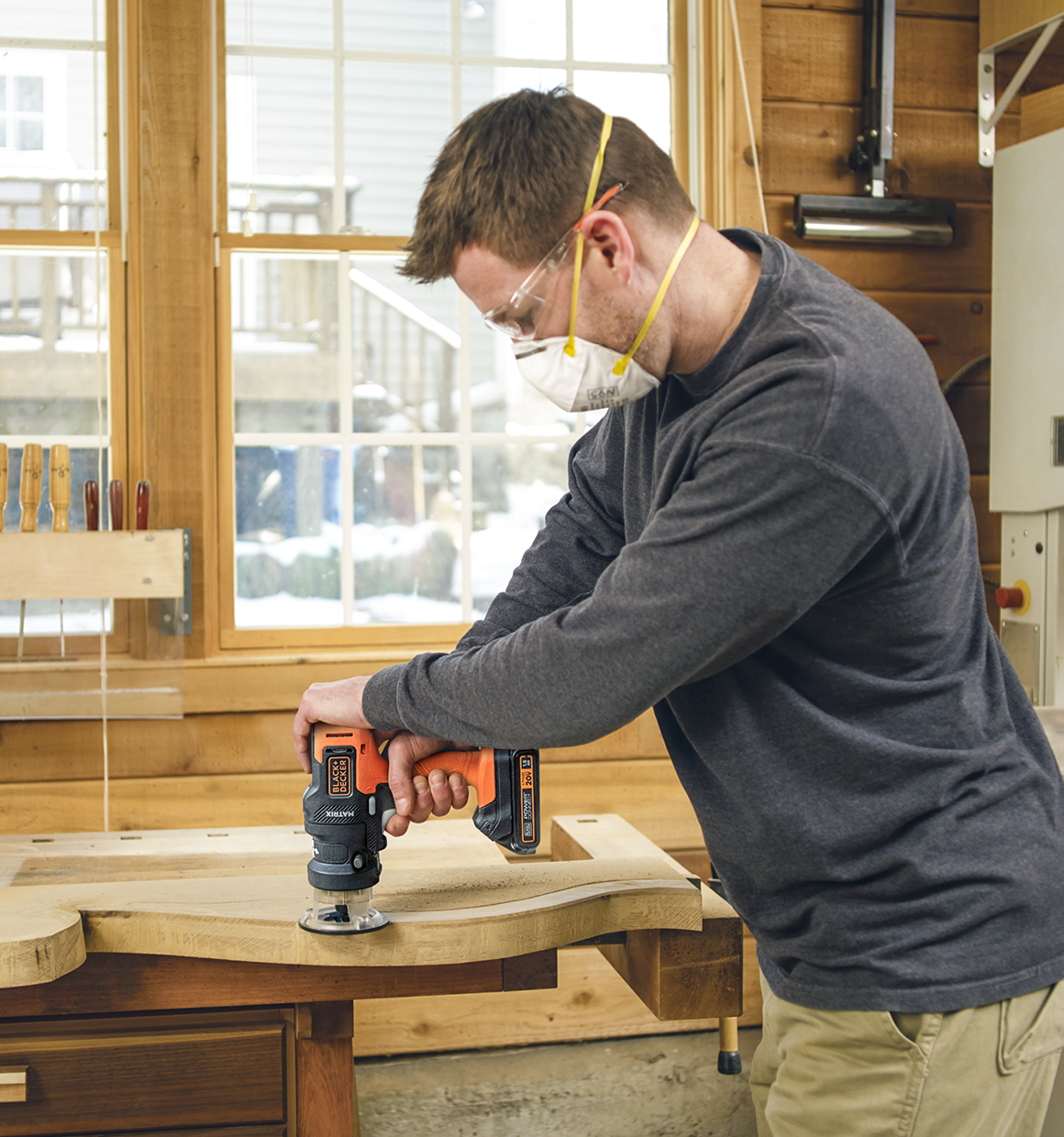 Man using a 20V Max Matrix Cordless Drill and Router attachment on a decorative piece of wood trim.