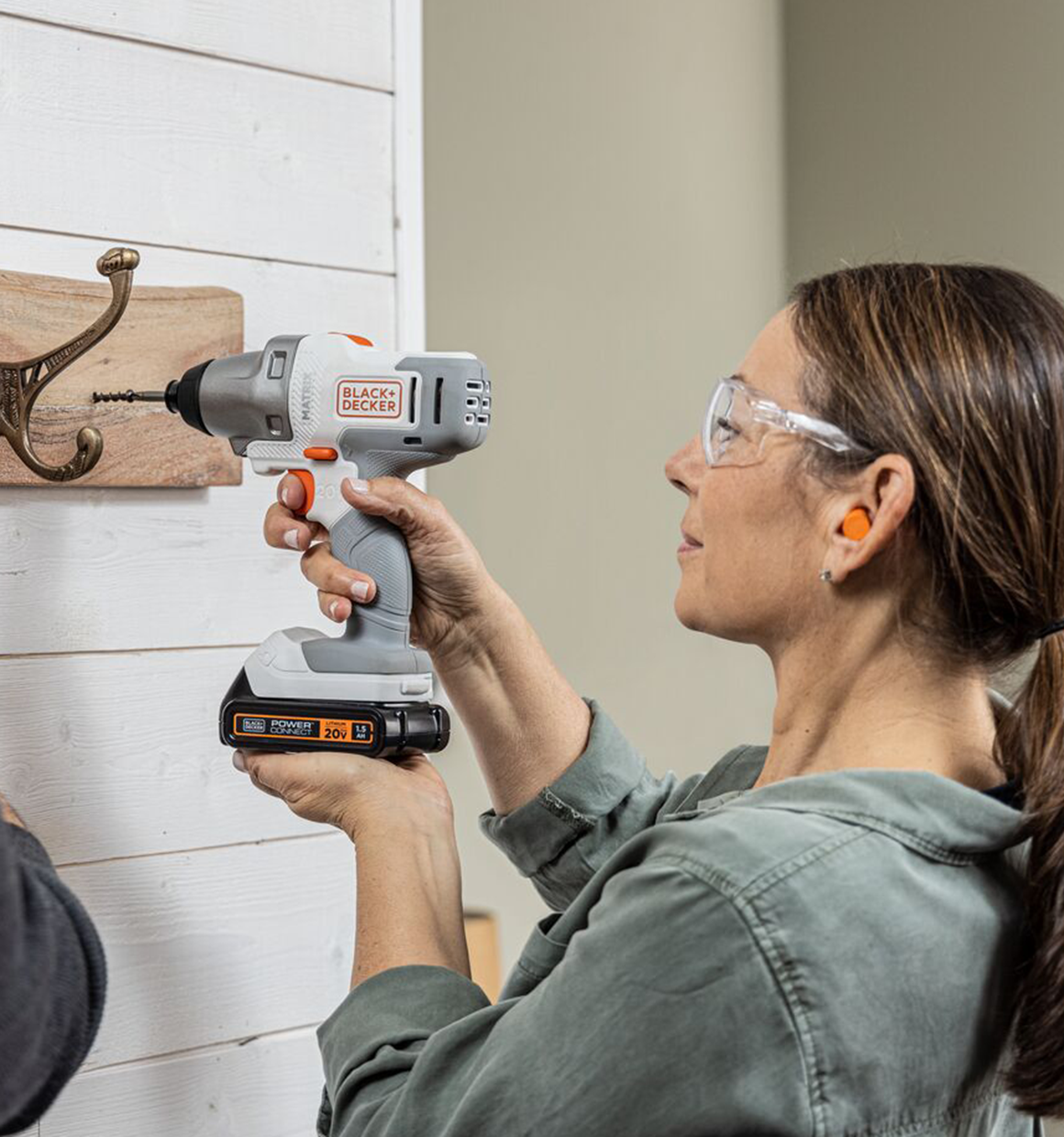Person uses the BLACK+DECKER MATRIX impact driver attachment to drive a light duty anchor in to the wall to hang a coat rack