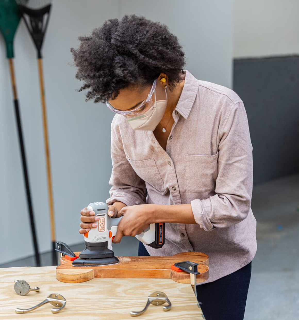 Person uses the BLACK+DECKER MATRIX sander attachment to sand the surface of a cornhole board for paint prep