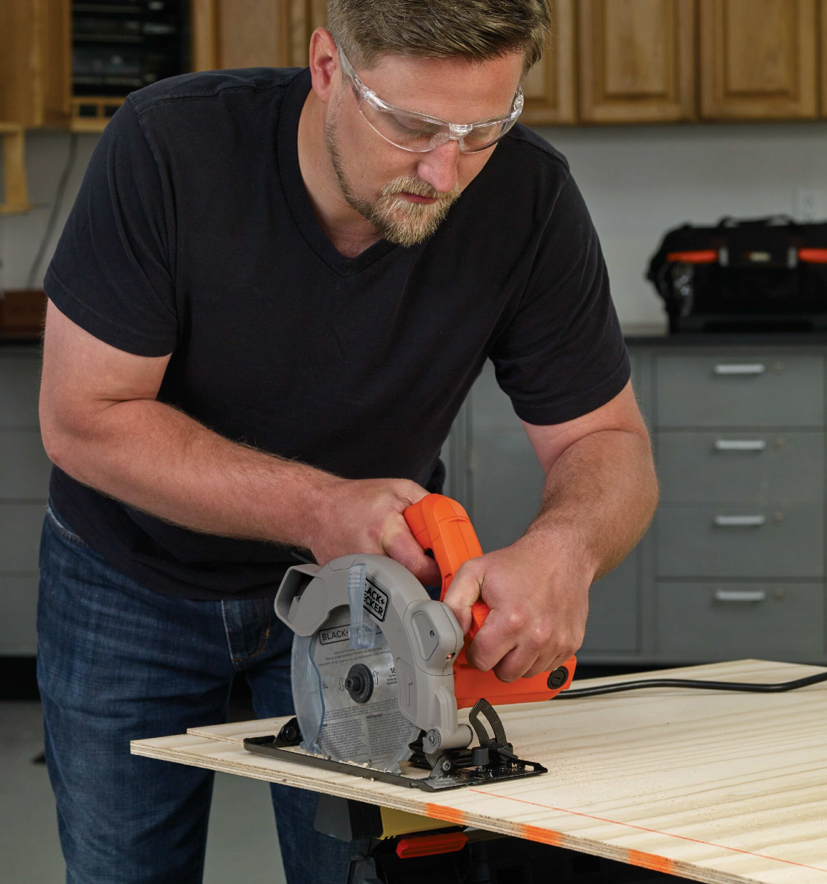 Man using a 7-1/4 Inch Circular Saw with Laser to cut plywood in a workshop.