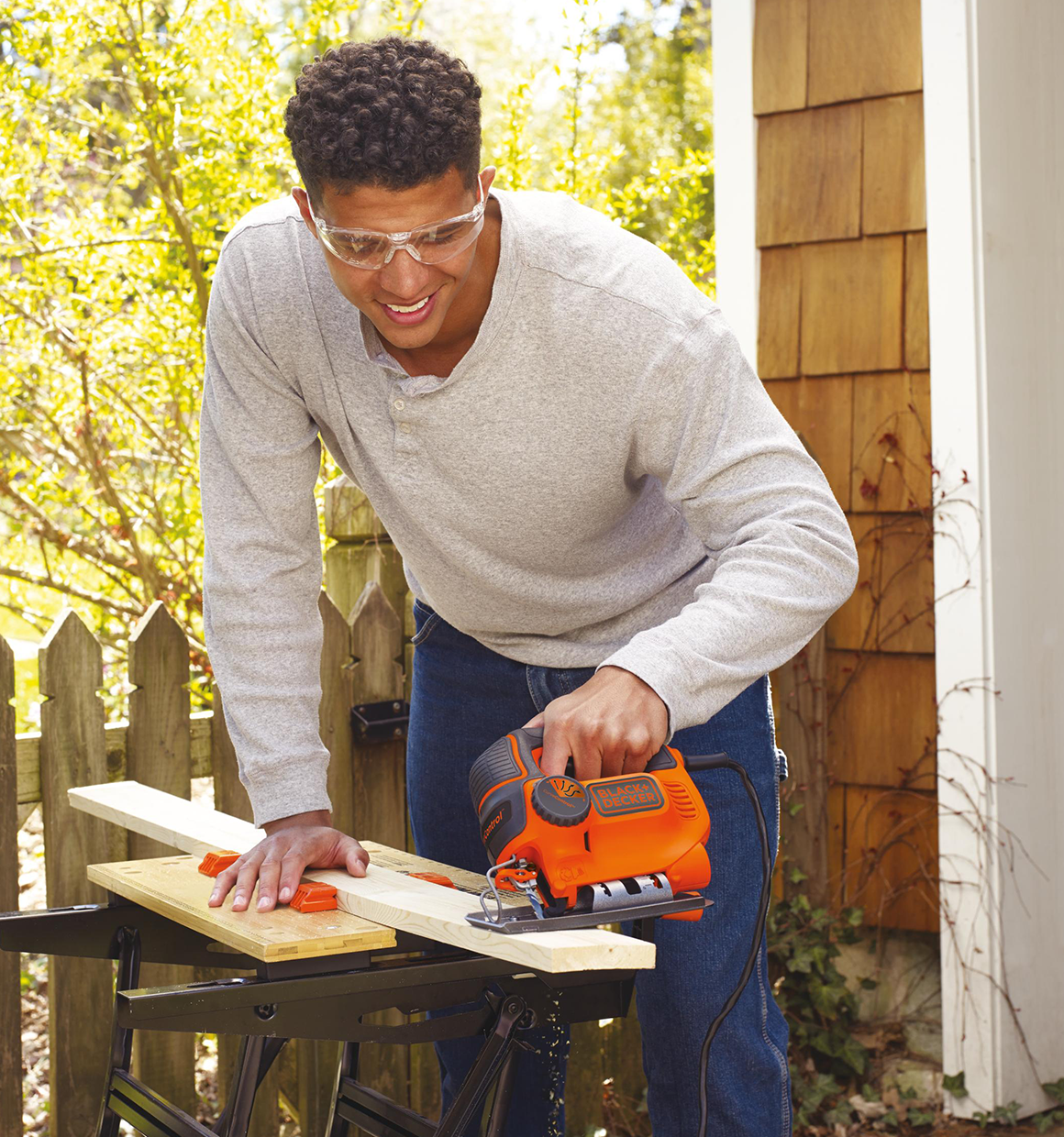 Man using Smart Select Jig Saw to cut plywood outside of garage.
