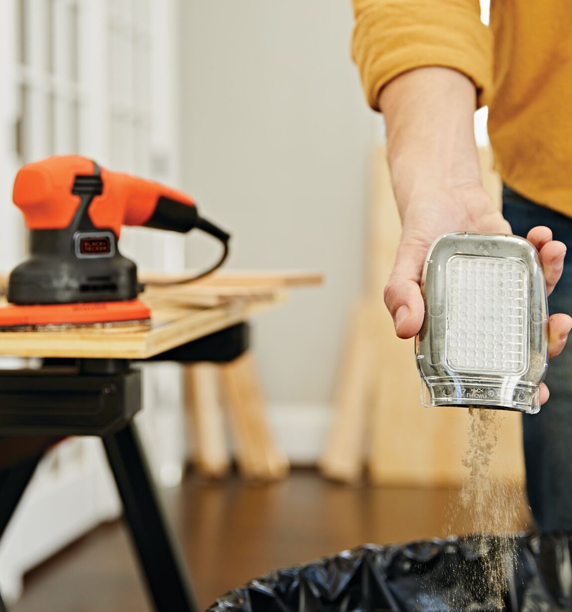 The dust collection canister of 1 point 2 ampere mouse sander being emptied.