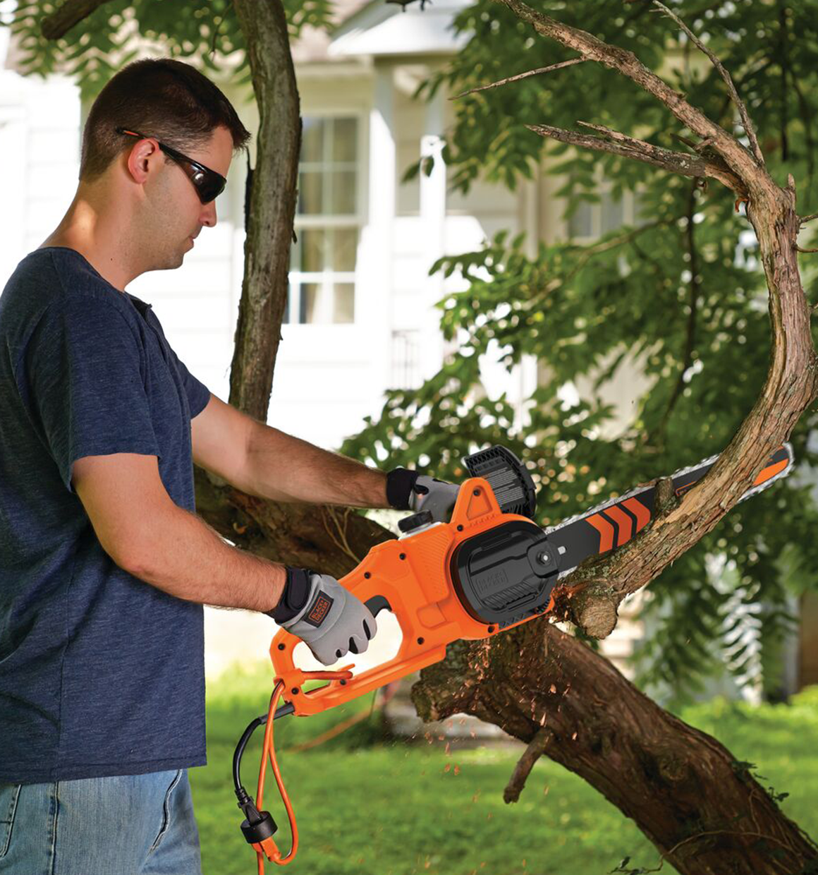 Person using Black and Decker 8 Amp 14 In. Electric Chainsaw to cut a tree branch.