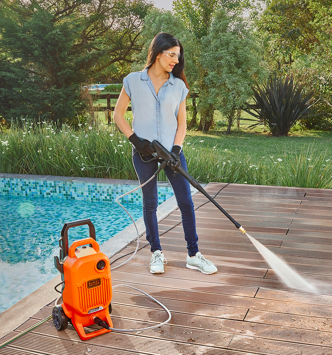 Woman cleaning a swimming pool deck with the BLACK+DECKER 1,850 MAX psi* pressure washer with 15˚ nozzle