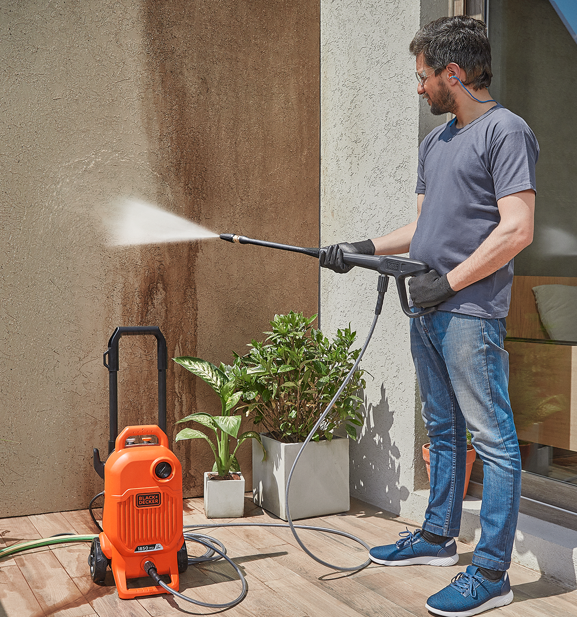 Man cleaning a porch wall with the BLACK+DECKER 1,850 MAX psi* pressure washer with turbo nozzle