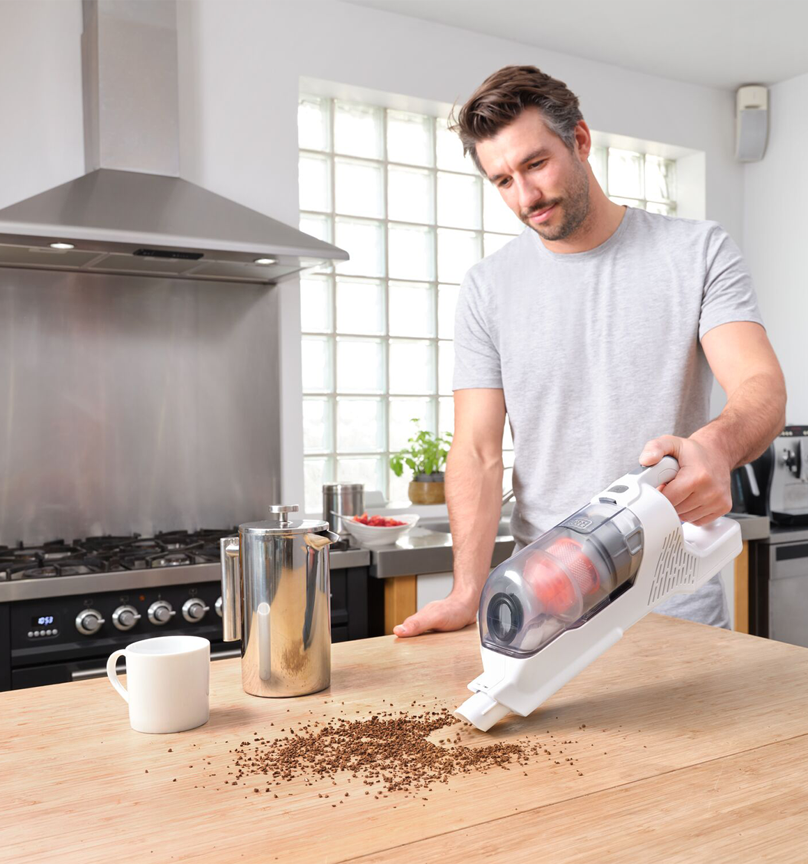 Powerseries plus cordless stick vacuum cleaning coffee grinds from wooden countertop.