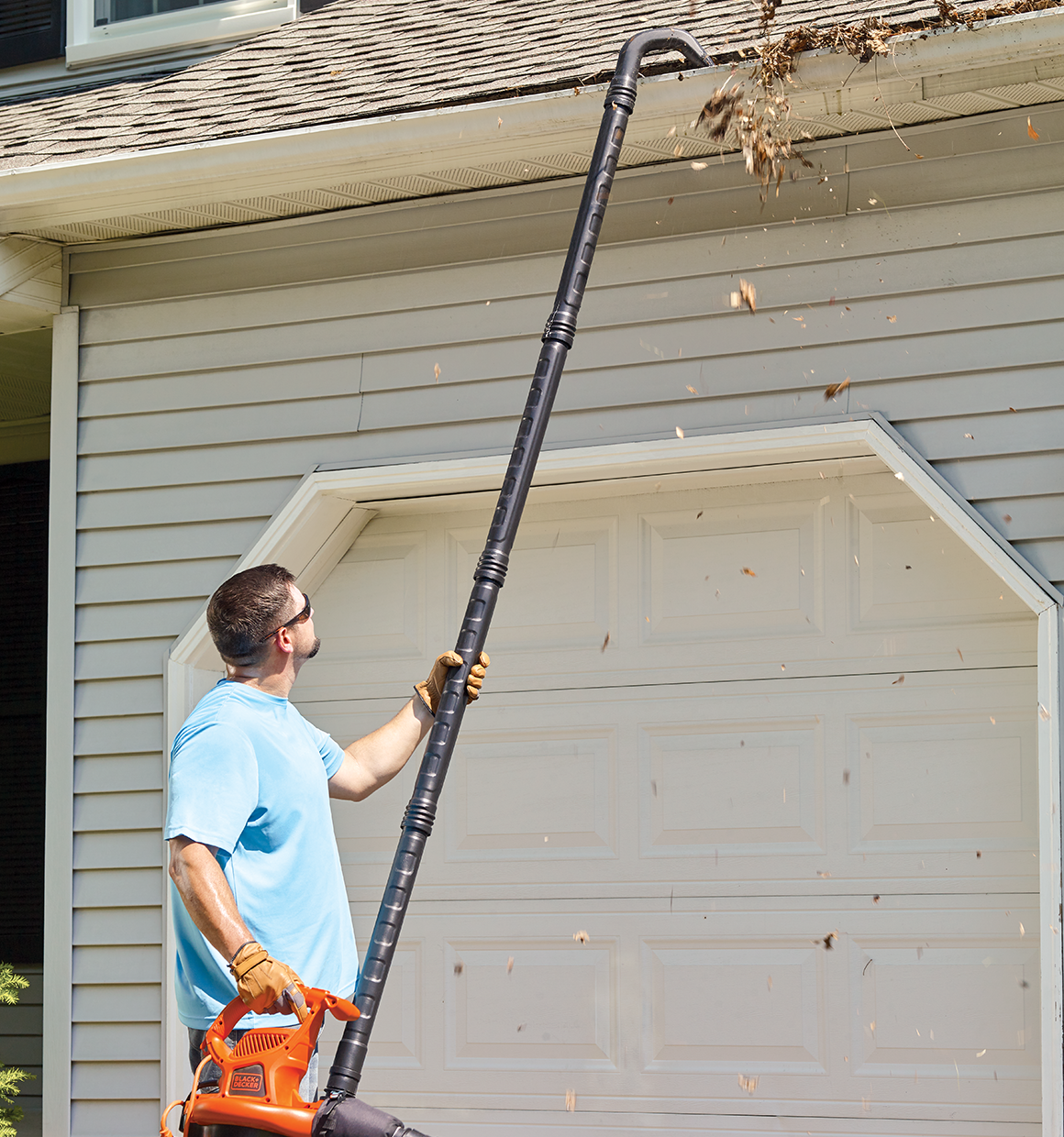 Gutter Cleaner Attachment being used used by person to blow leaves and debris out of roof gutter.
