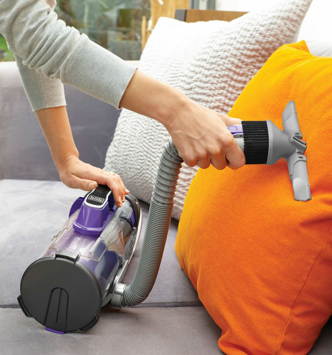 Black and decker powerseries pro cordless 2 in 1 pet vacuum being used to clean an orange throw pillow.