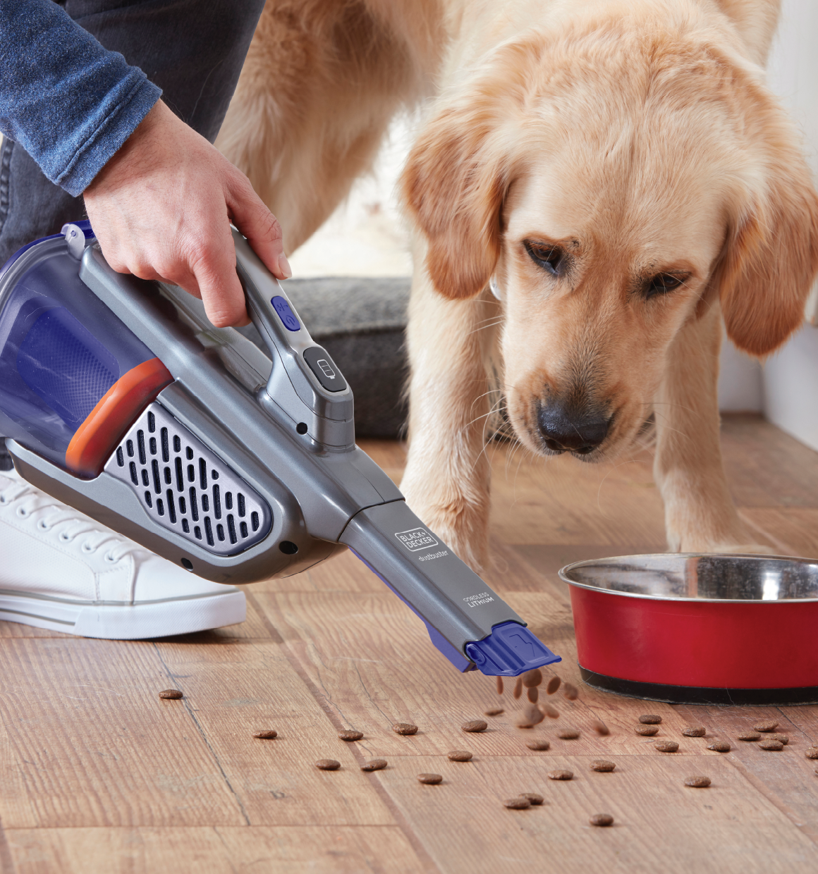 20 volt dustbuster advanced clean pet hand vacuum with base charger and extra filter being used to clean up spilled dog food next to dog and dog food bowl.