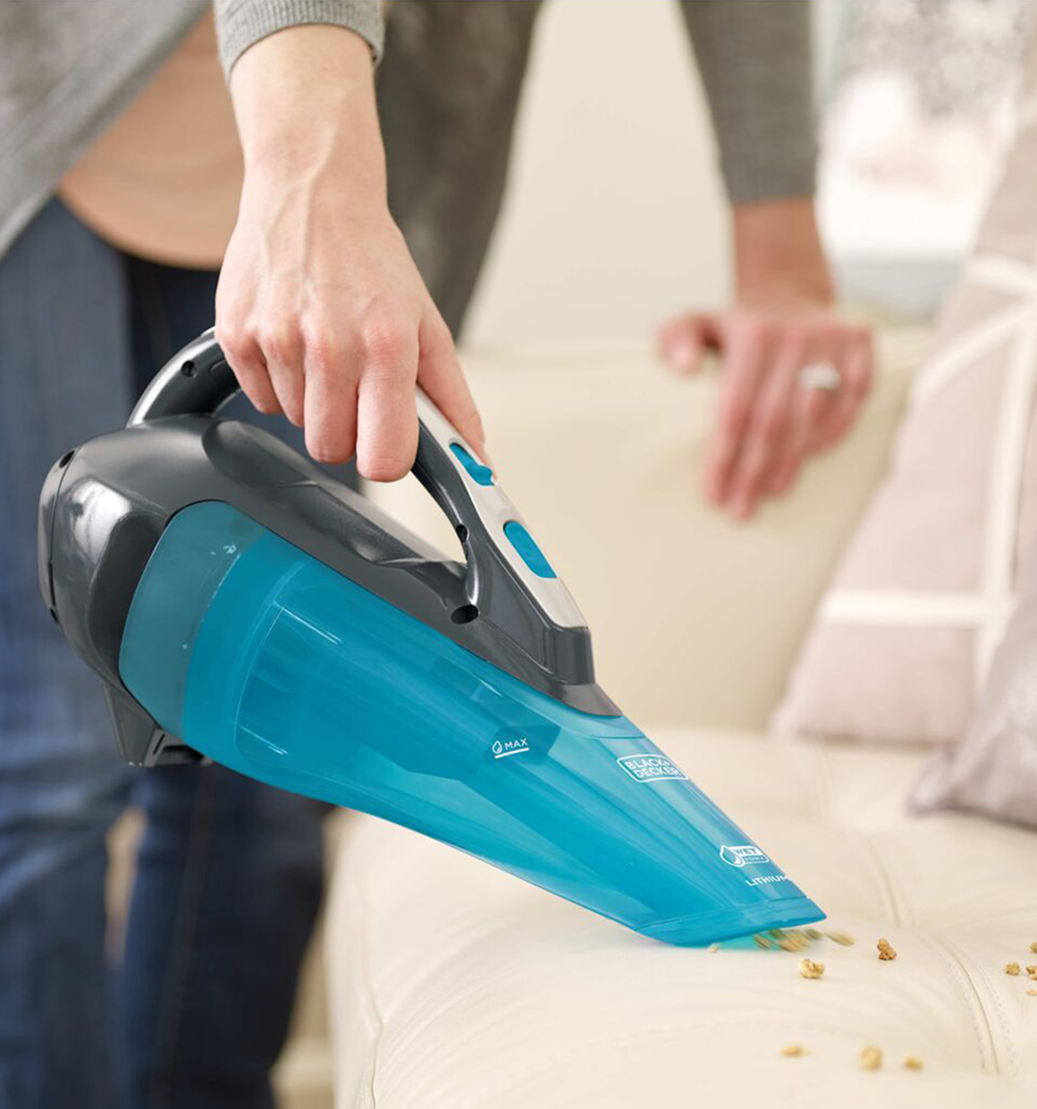 Black and Decker dustbuster advanced clean wet and dry cordless hand vacuum being used to clean up a mess on a couch.