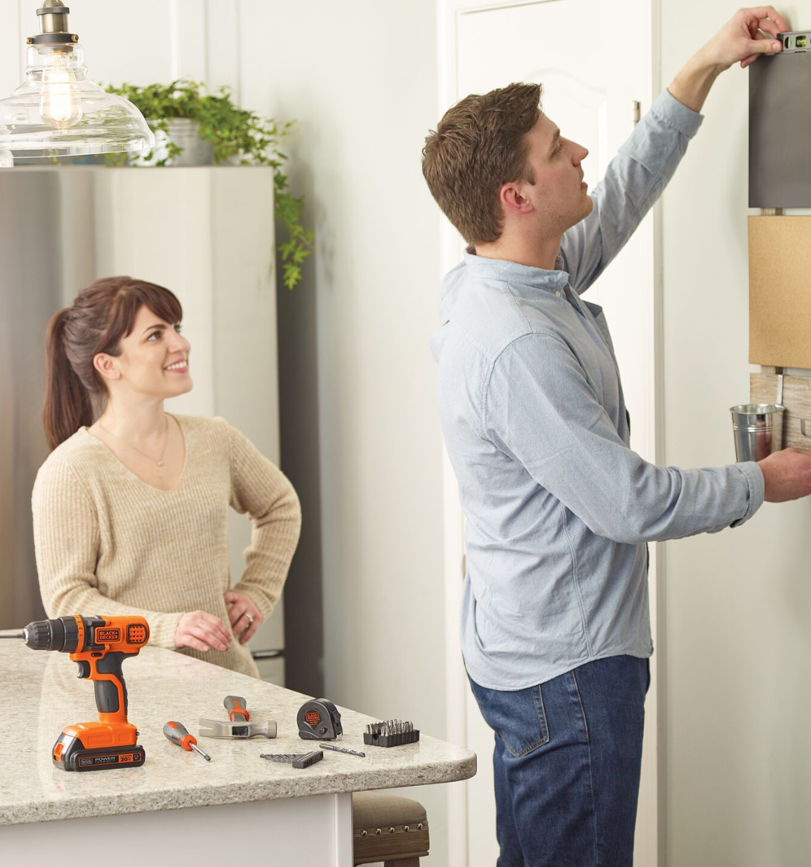 Man and woman in a kitchen with Home Tool Kit on the counter.