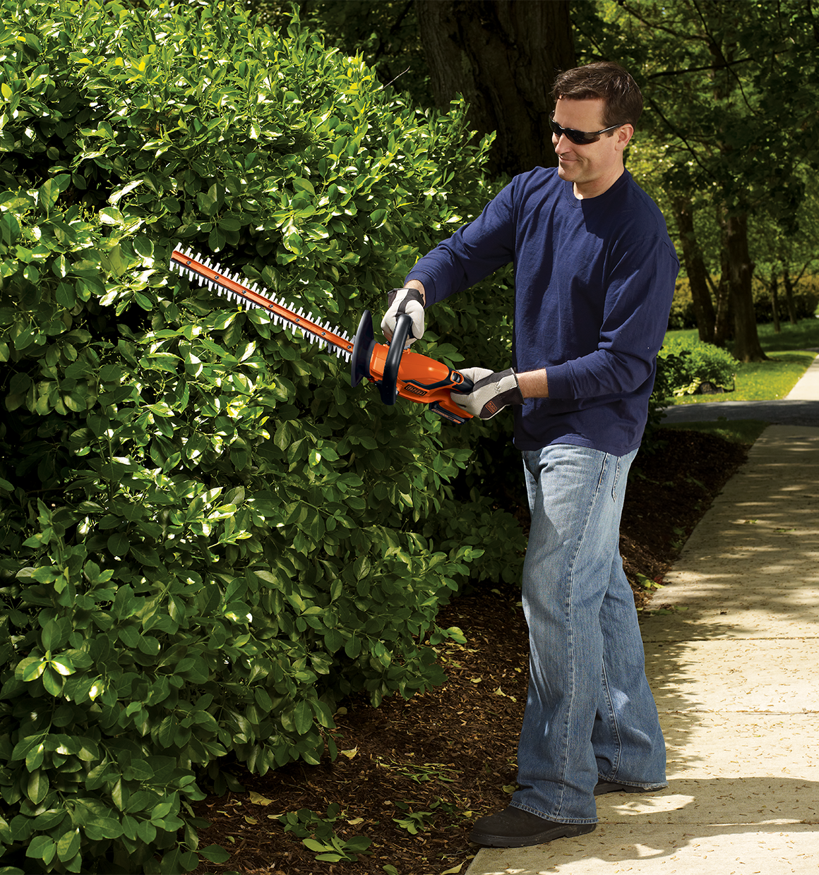 Lithium 22 inch Hedge Trimmer being used by person to trim bushes.