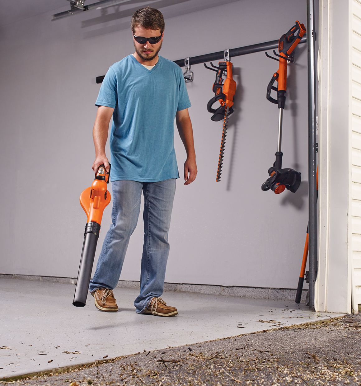 SMARTECH 20 Volt MAX POWERBOOST Sweeper being used by a person to clear debris from a garage.